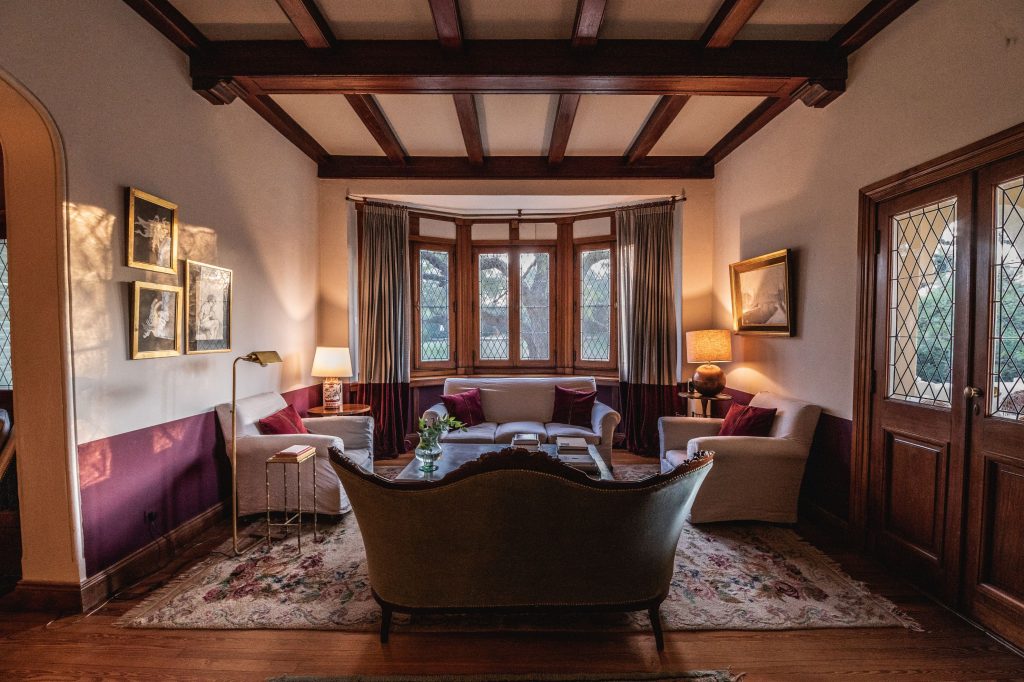 Sala de estar en Scratch House con sillones y grandes ventanales que permiten el ingreso de luz natural